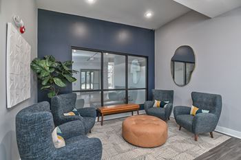 a lounge area with blue chairs and a table and a window